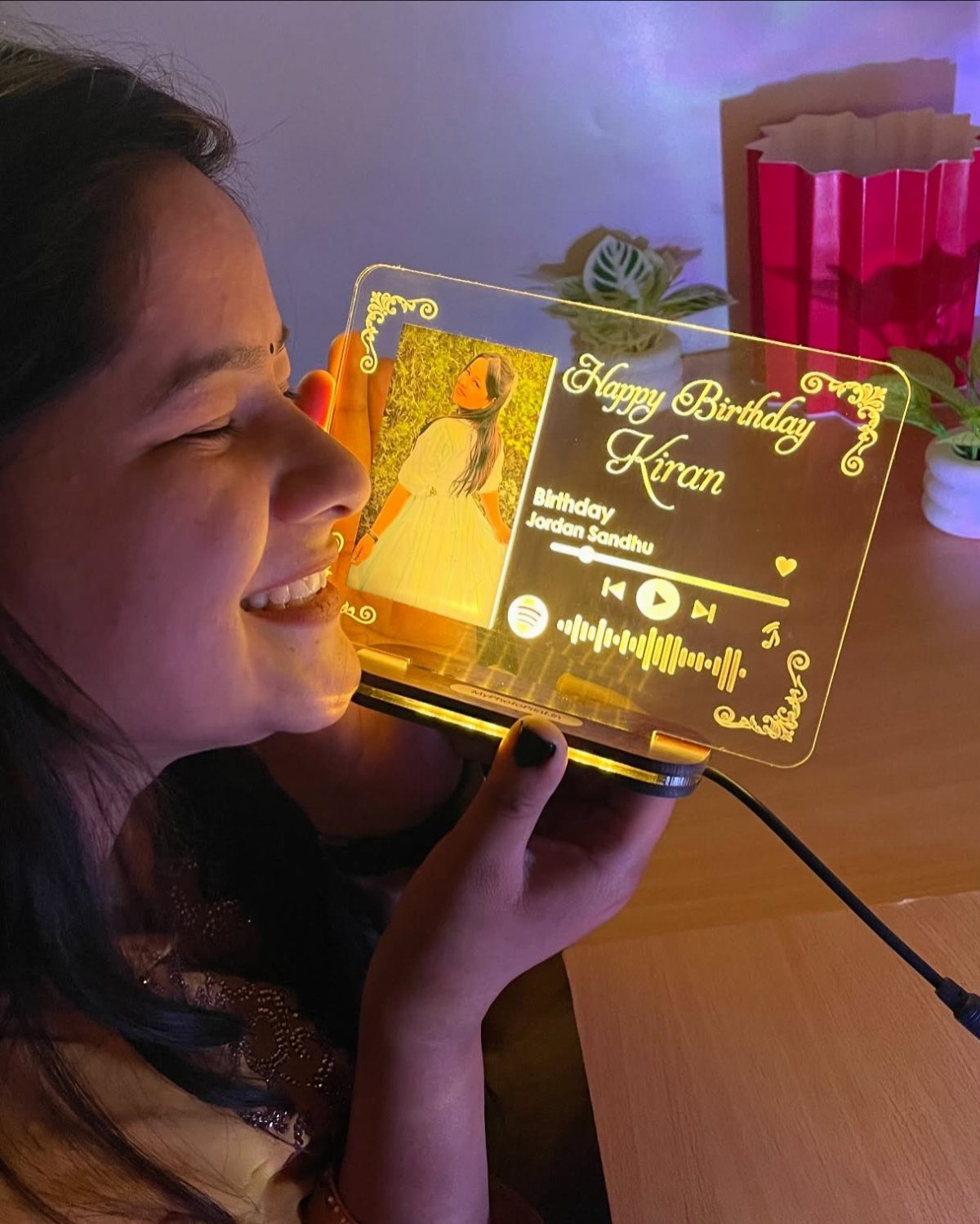 Woman holding a glowing acrylic plaque with a photo and sound wave art.