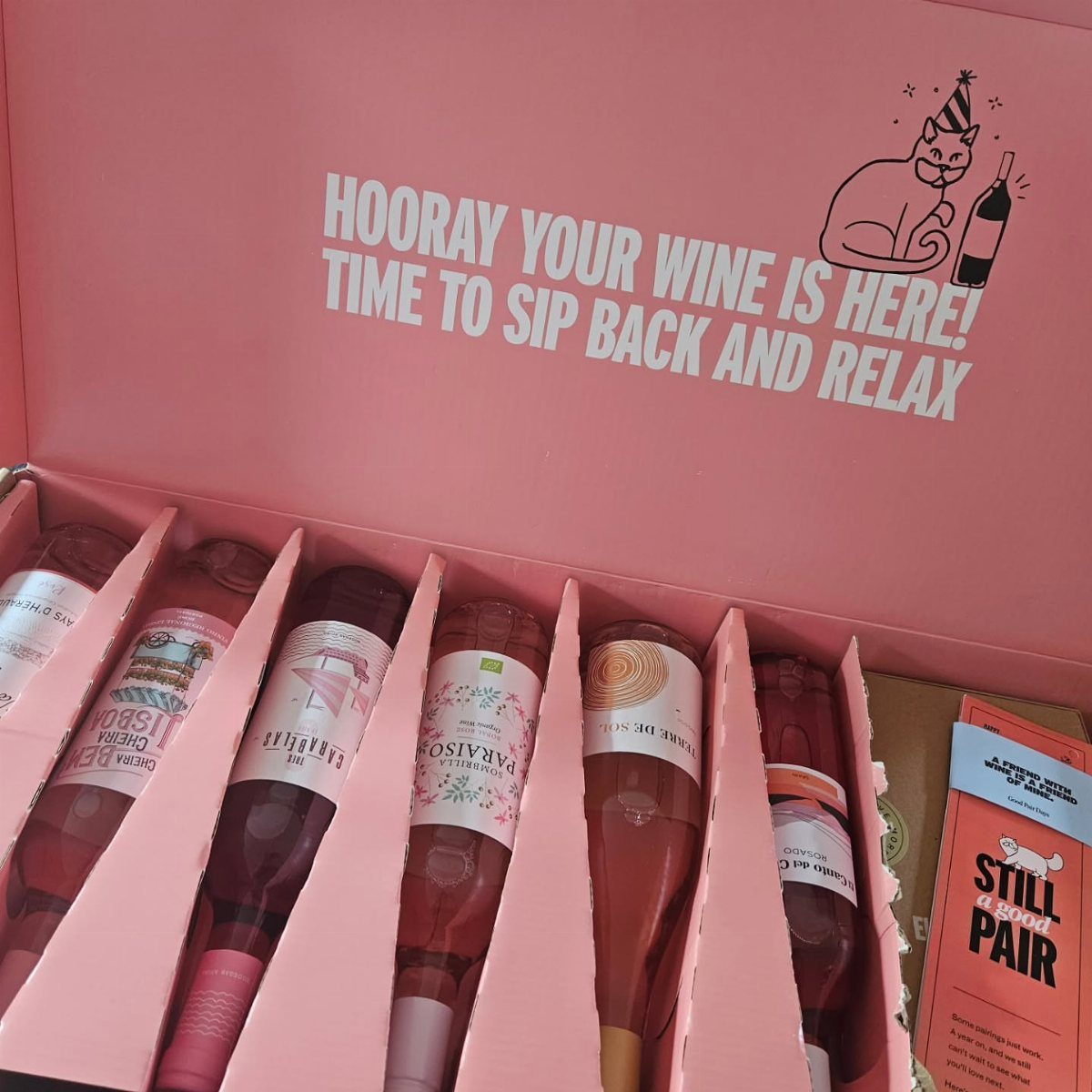 Six bottles of rosé wine inside a pink delivery box with a cat illustration.