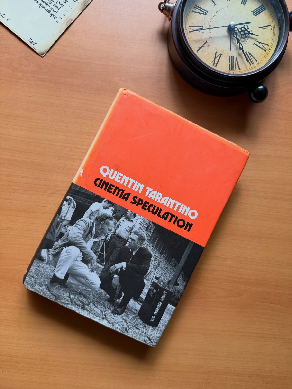 Quentin Tarantino Cinema Speculation book on a wooden table next to a clock.
