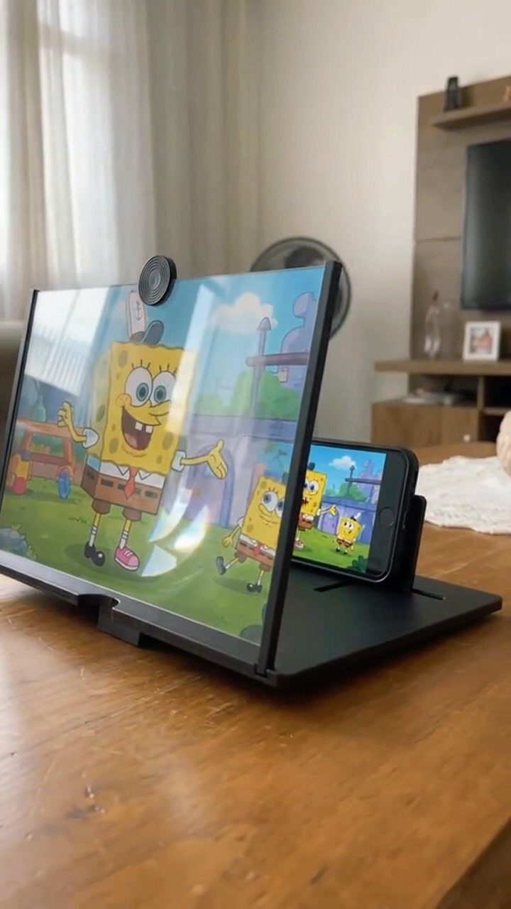 Smartphone screen magnifier on a wooden table displaying a cartoon character.