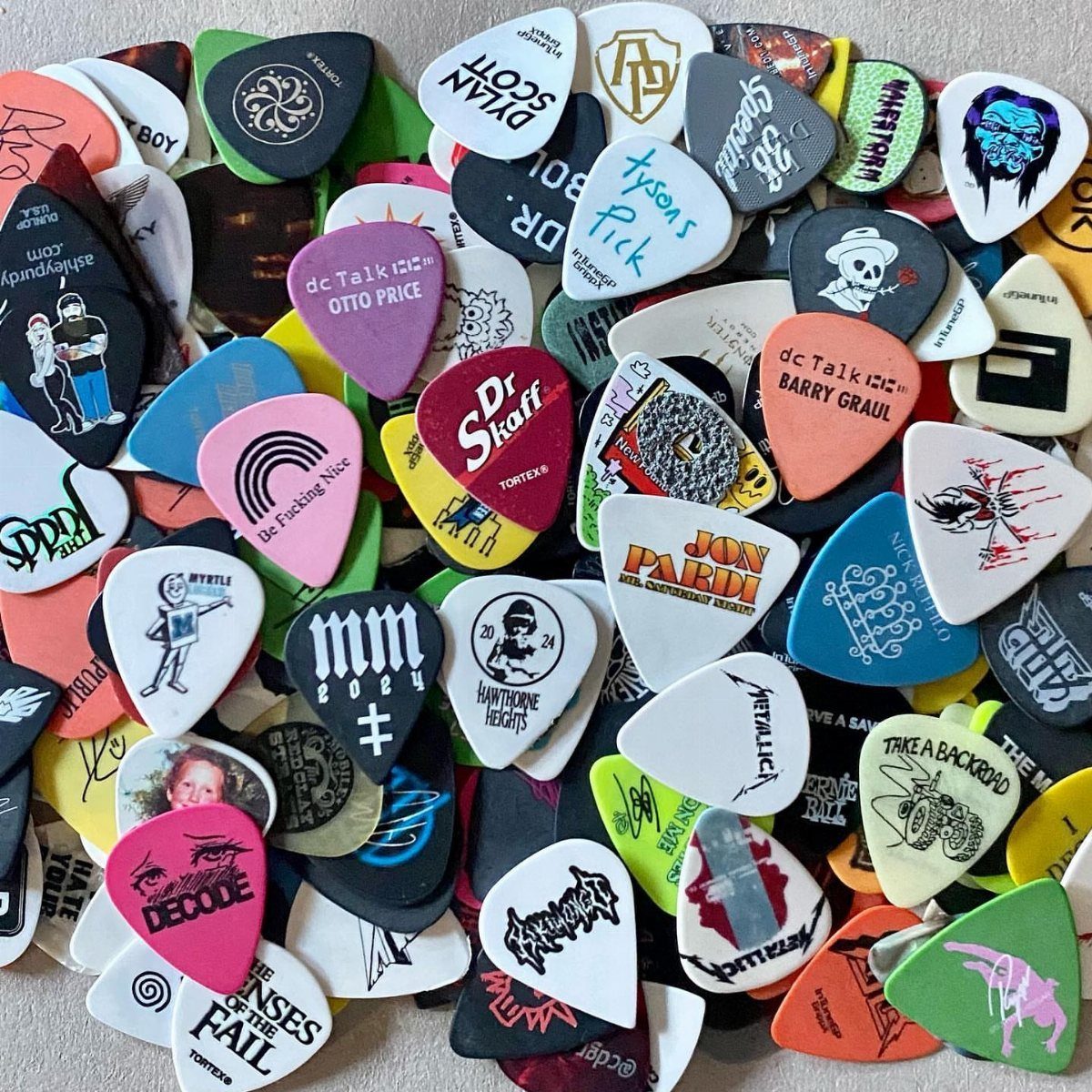A pile of colorful guitar picks with various logos and text scattered together.