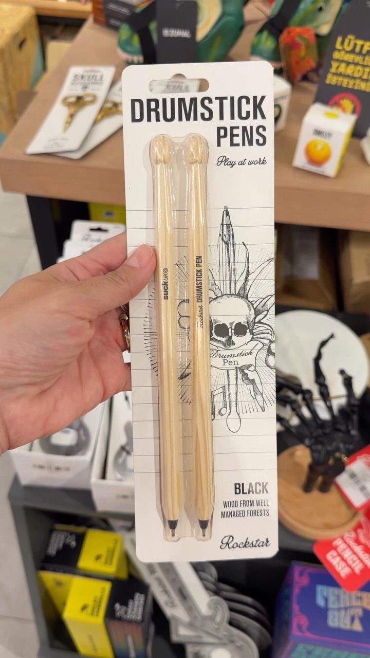 Two drumstick-shaped pens in a white retail package held by a hand.