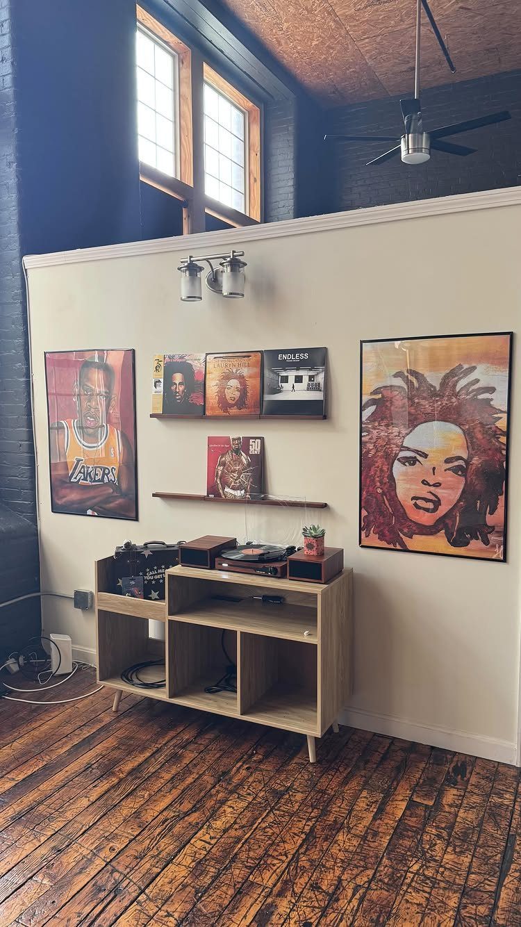 Framed music art prints on a wall above a wooden audio console