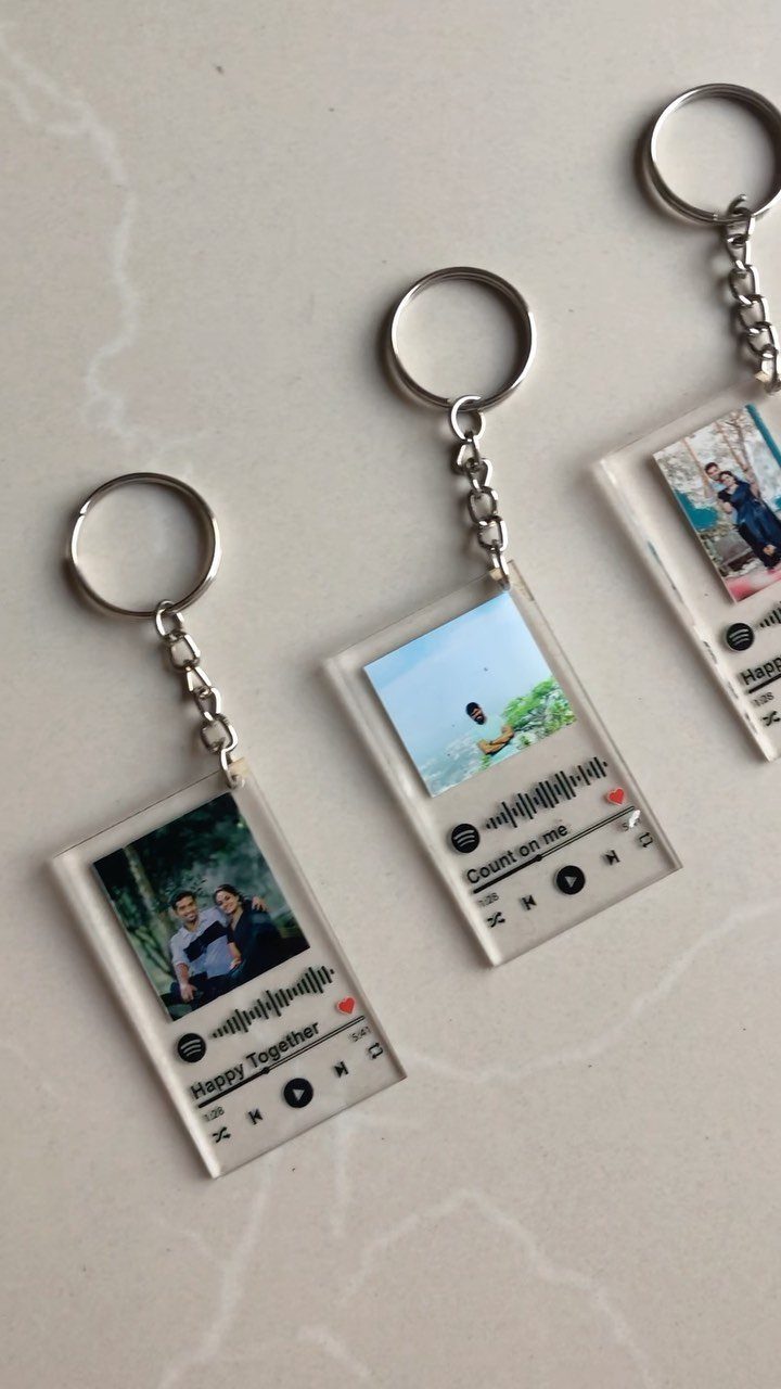 Three acrylic keychains featuring photos and Spotify song codes on a white surface.