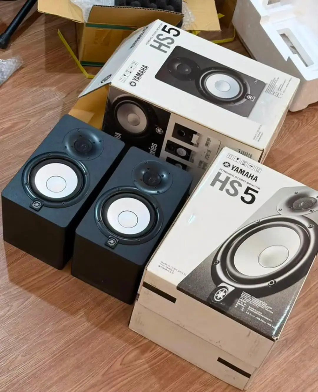 Two black Yamaha HS5 studio monitors and their original packaging on wooden flooring.