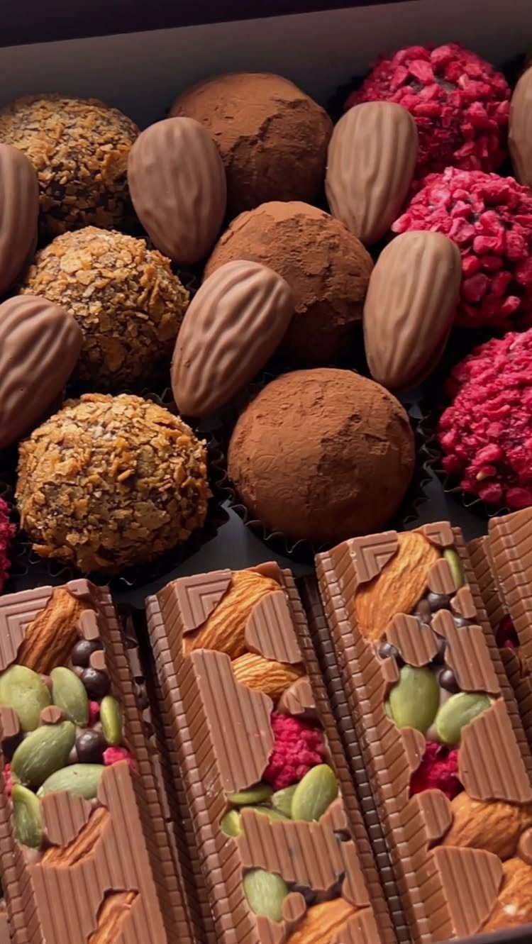 Assorted gourmet chocolates including truffles and nut-filled bars in a gift box.