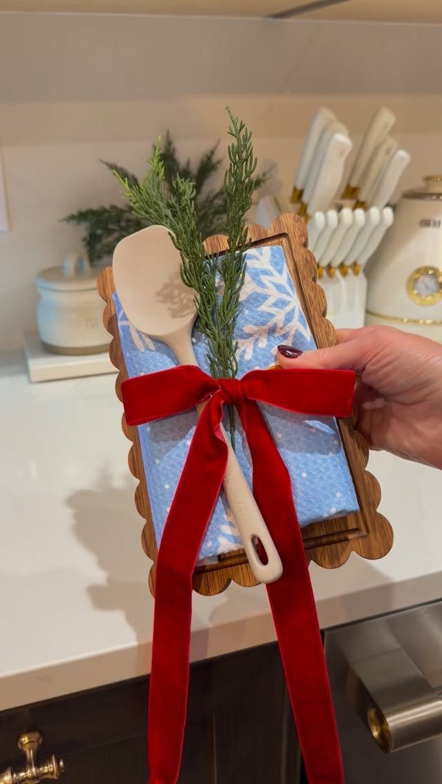 Gift set with wooden spoon, blue towel, and red ribbon on wooden board