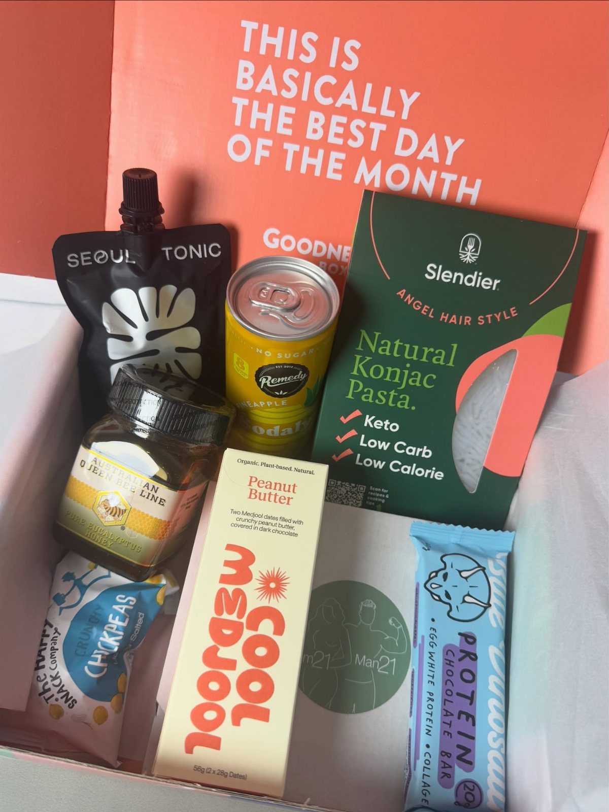 Assorted healthy snacks and drinks arranged inside a pink subscription gift box.
