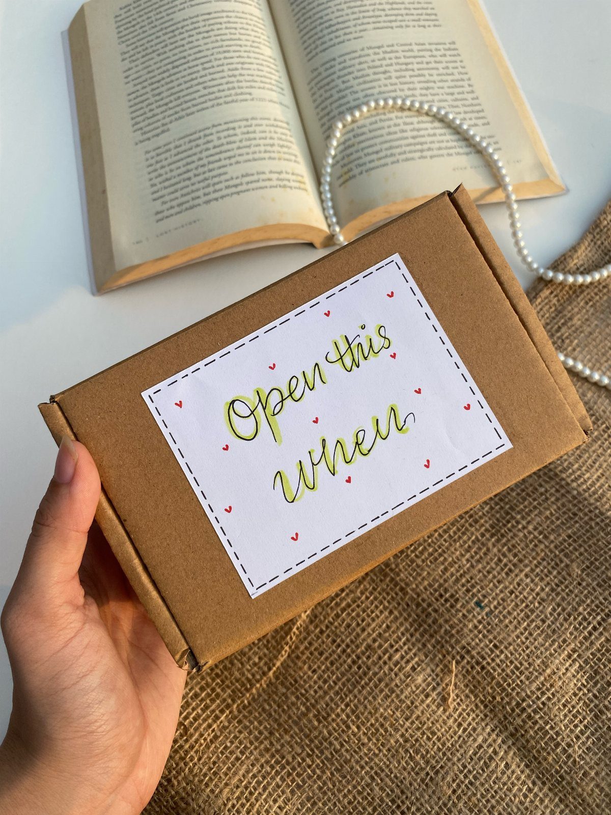 Cardboard gift box with a handwritten label held over an open book.