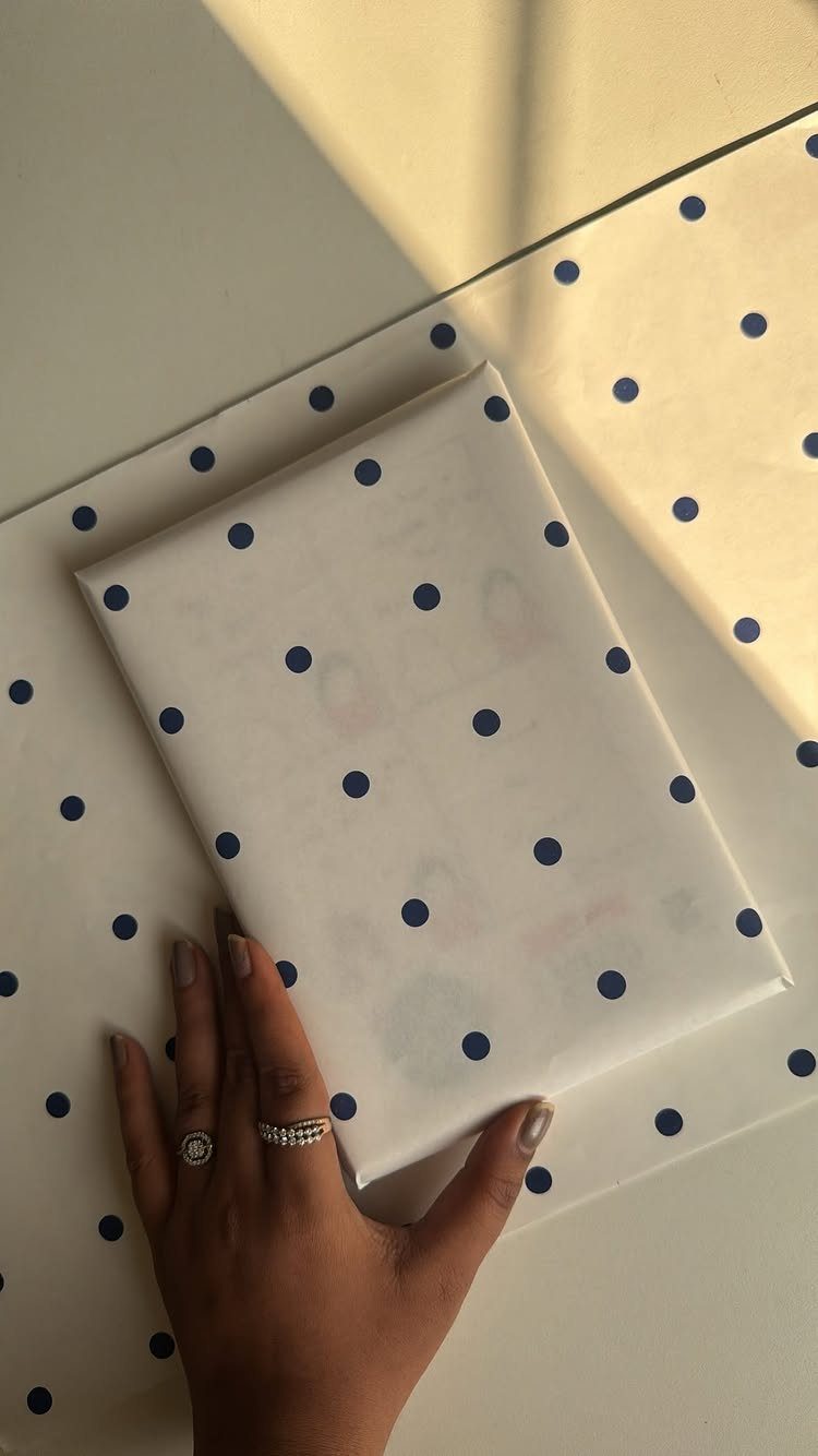 Wrapped gift and wrapping paper featuring a white background with blue polka dots.