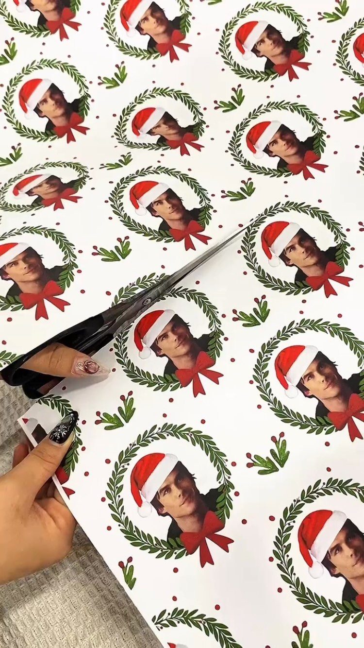 Custom wrapping paper with a man's face in Santa hats being cut by scissors.