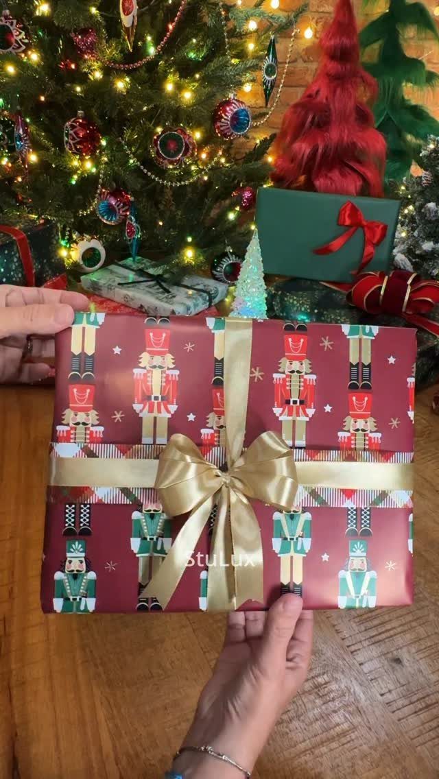Wrapped gift with burgundy nutcracker pattern paper and a gold satin bow.