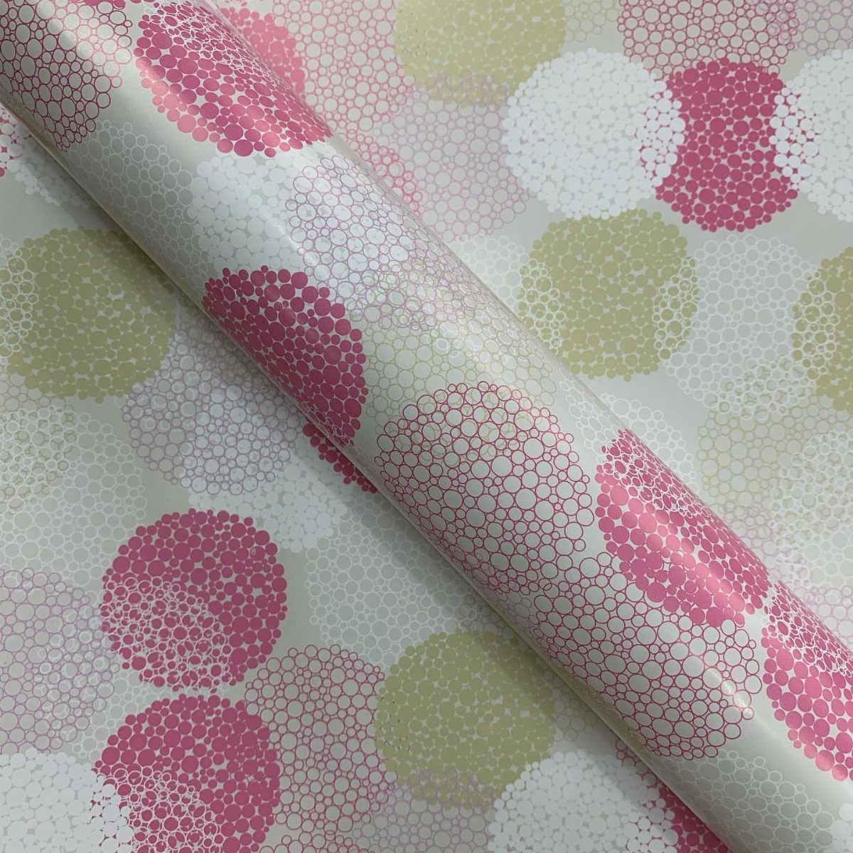White wrapping paper roll with a pattern of pink and gold textured circles.