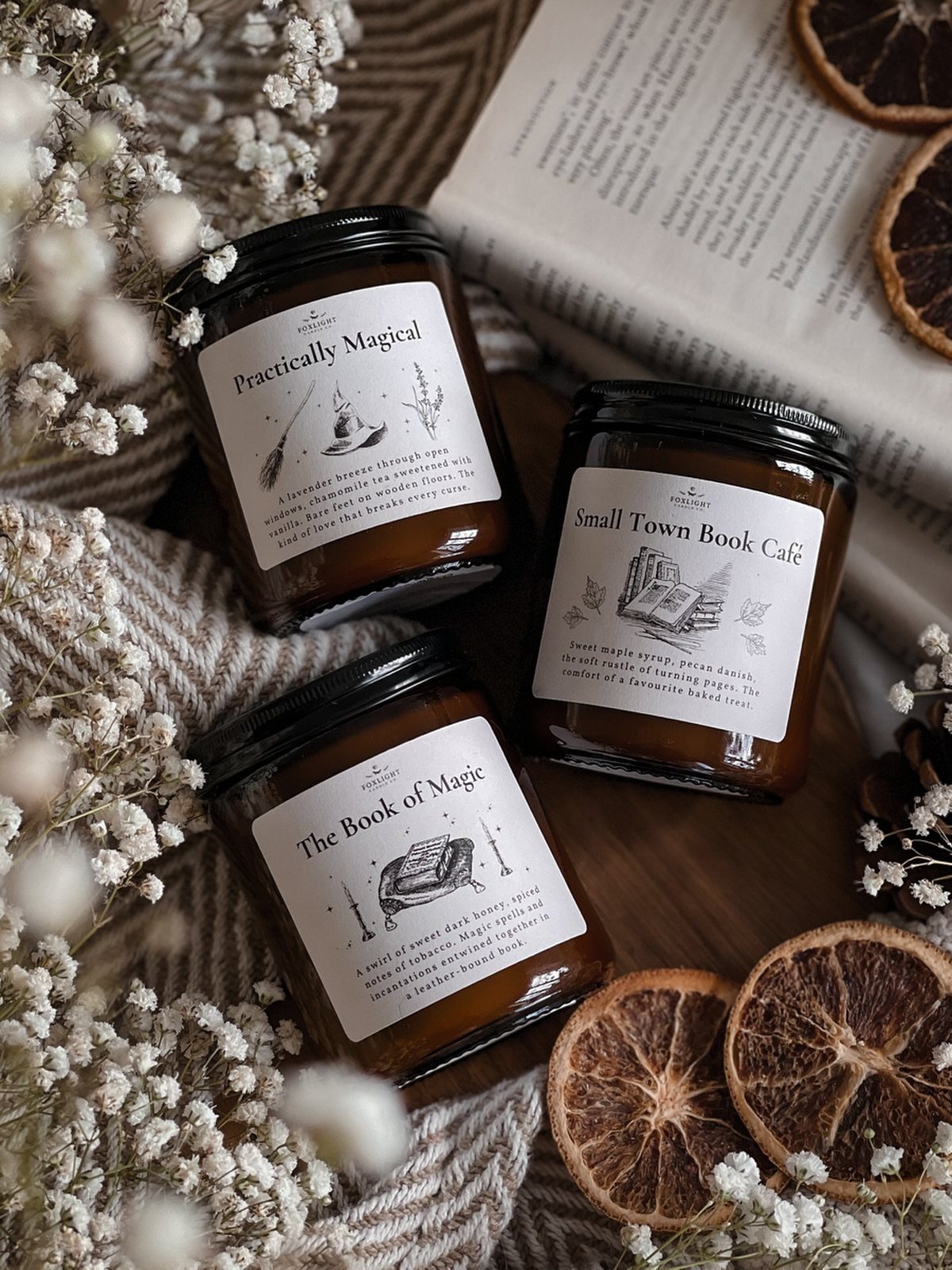 Three literary themed candles arranged with an open book and dried orange slices.