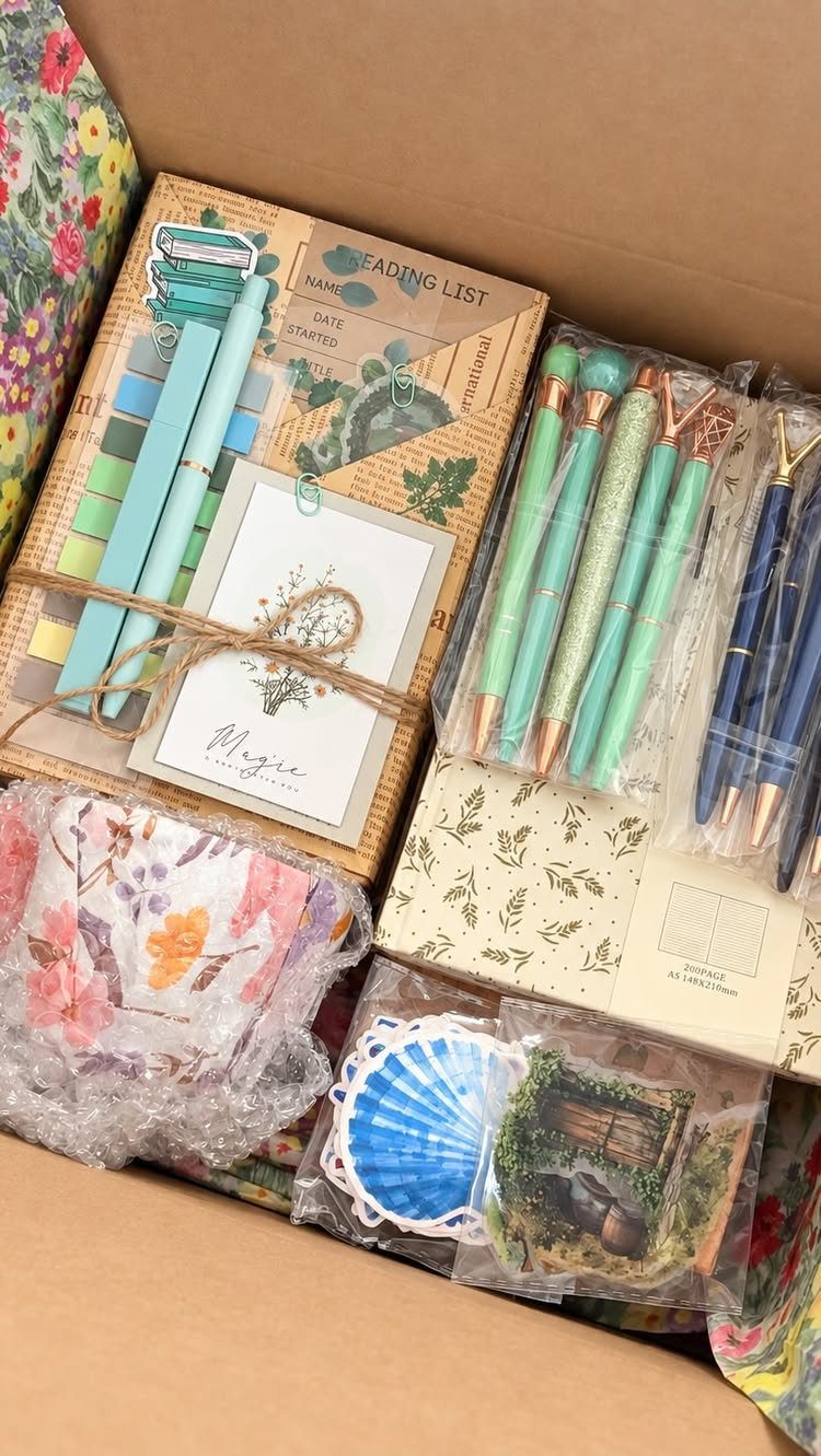 Gift box with a reading list notebook, teal pens, and floral stationery items.