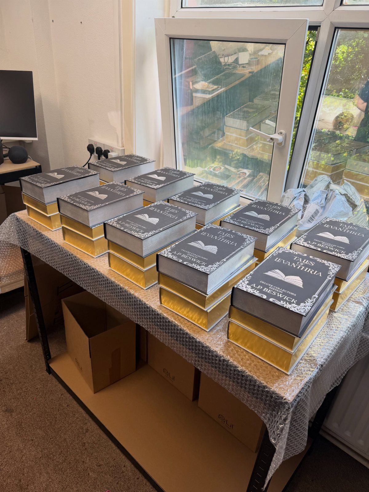 Special-edition hardcover books with grey and gold ornate covers arranged on a table.