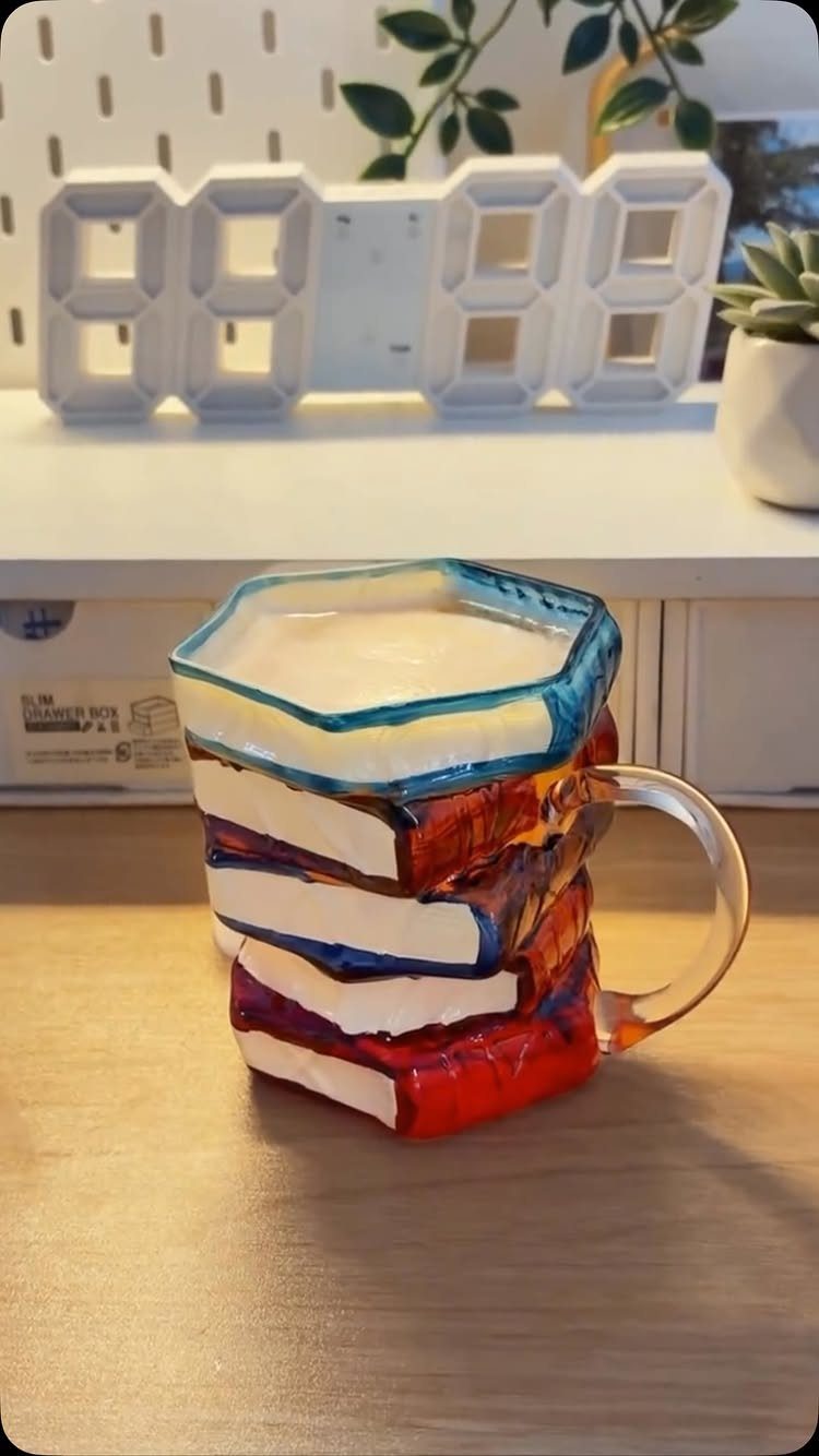 Ceramic mug shaped like a stack of colorful books filled with coffee.
