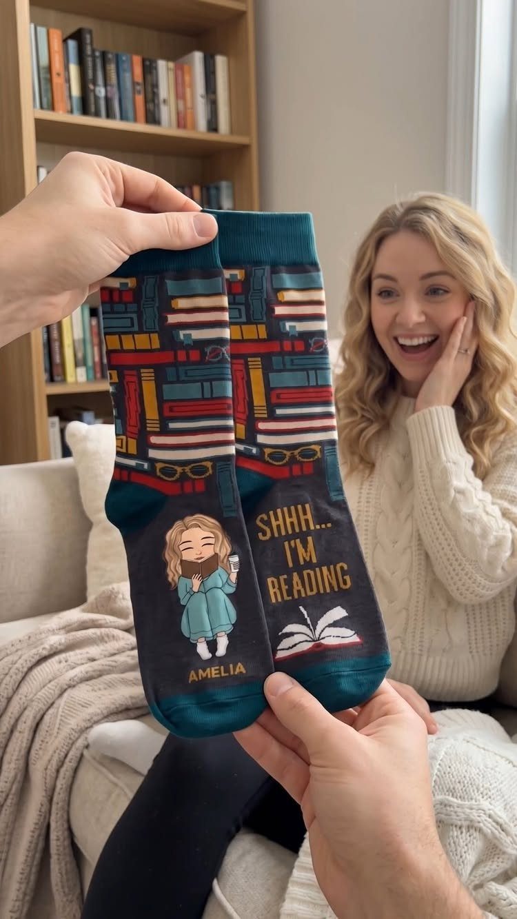 Book-themed socks with colorful book stacks held up for a surprised woman.