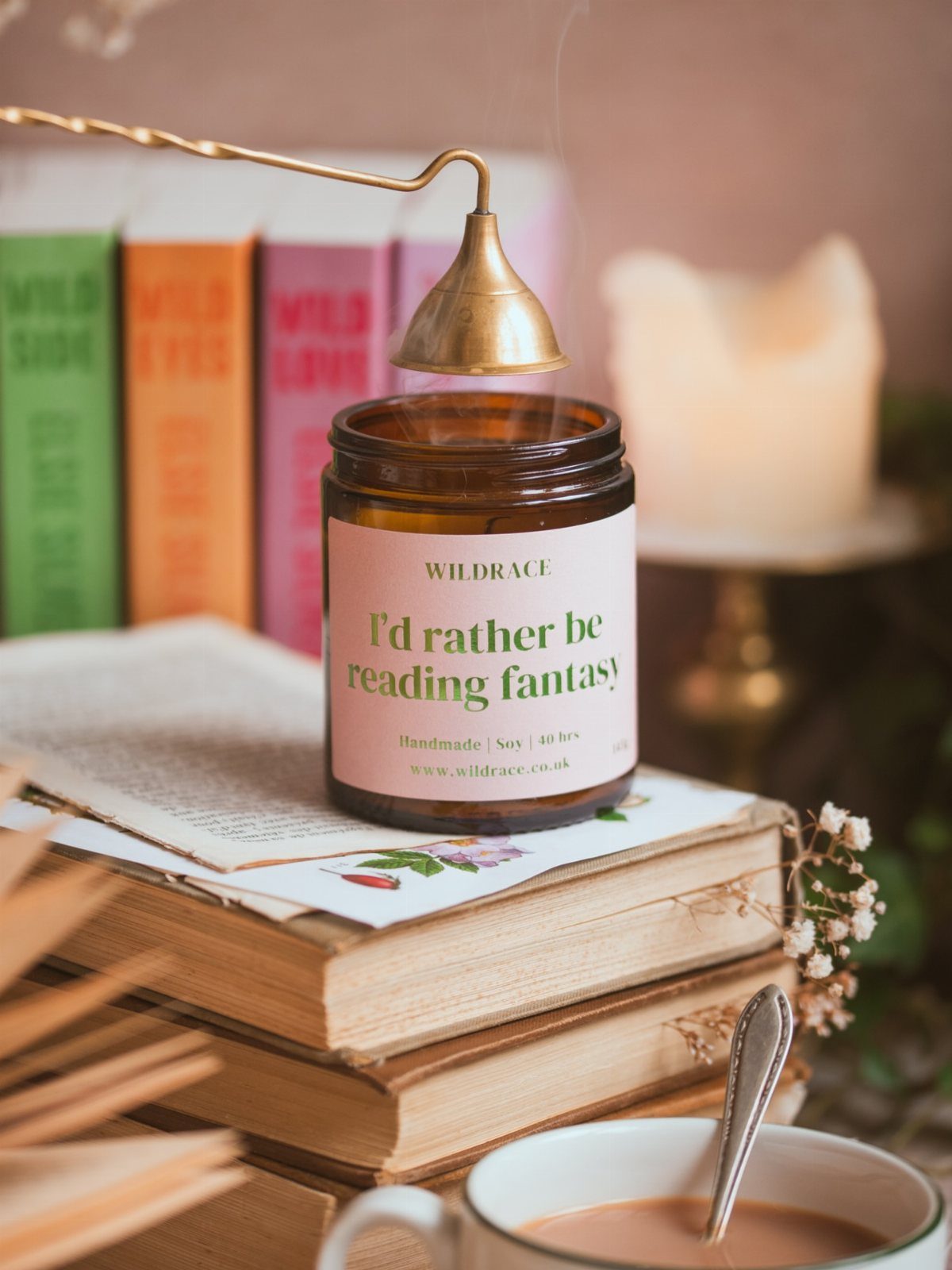 Amber glass candle with book-themed label resting on a stack of vintage books.