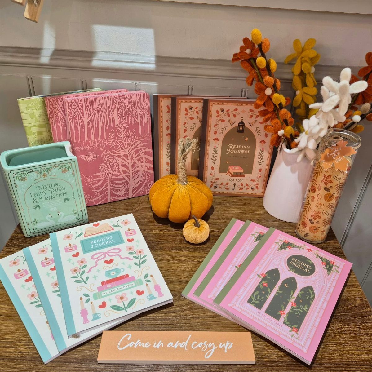 Reading journals with colorful covers arranged with a pumpkin and autumn flowers.
