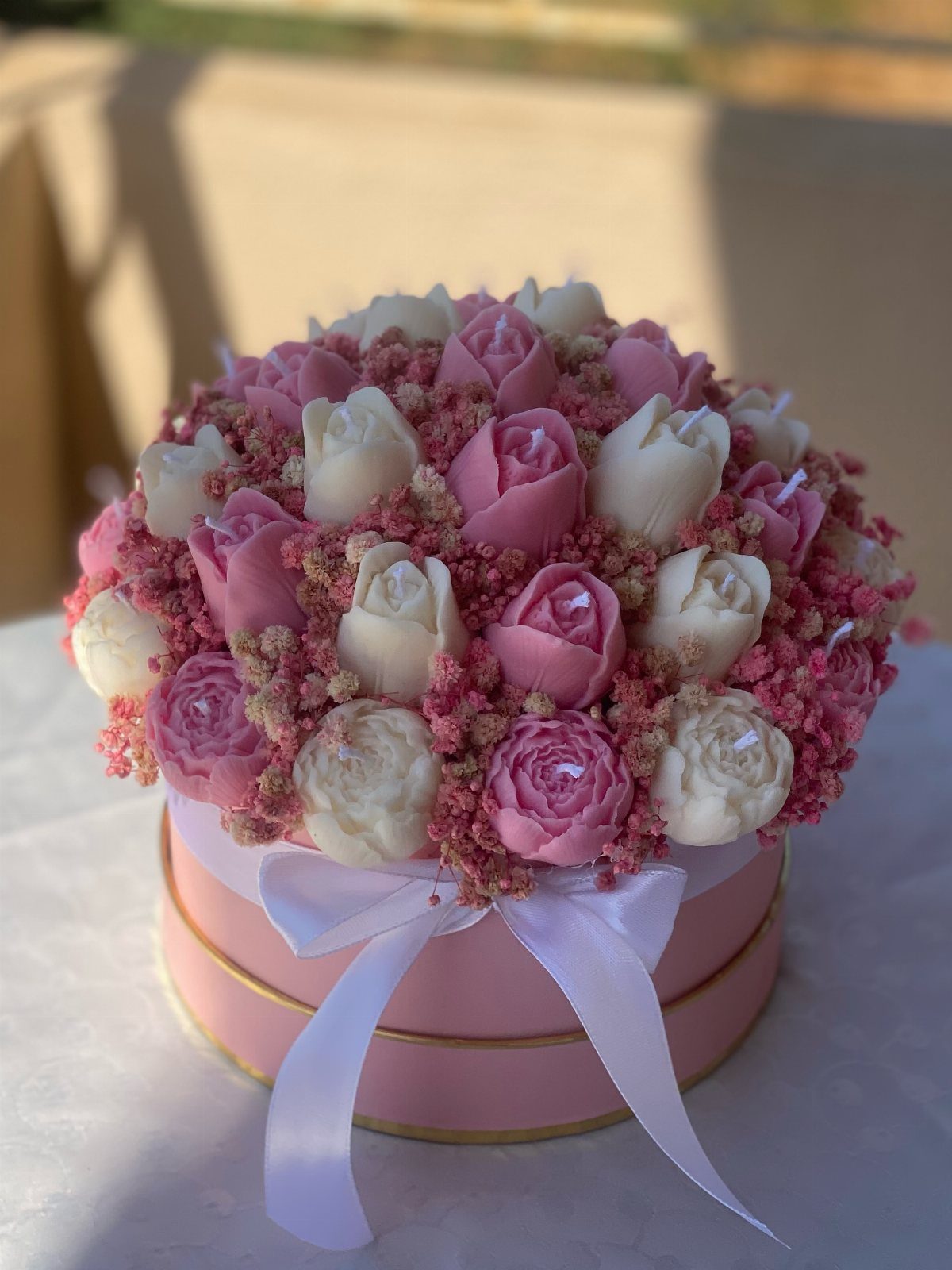 Pink gift box filled with rose-shaped chocolates and pink dried flowers.