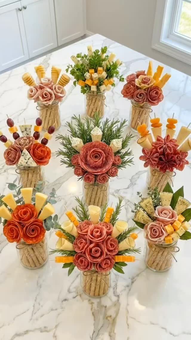 Charcuterie bouquets made of meat and cheese in glass jars on marble counter