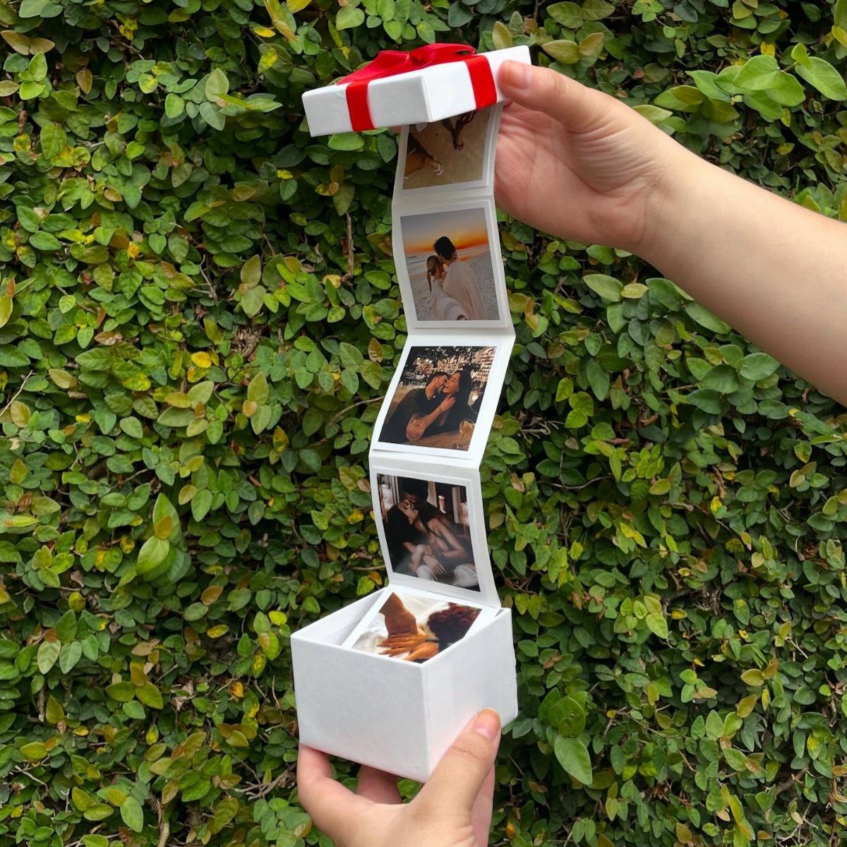 White gift box with a red ribbon opening to reveal a photo strip.