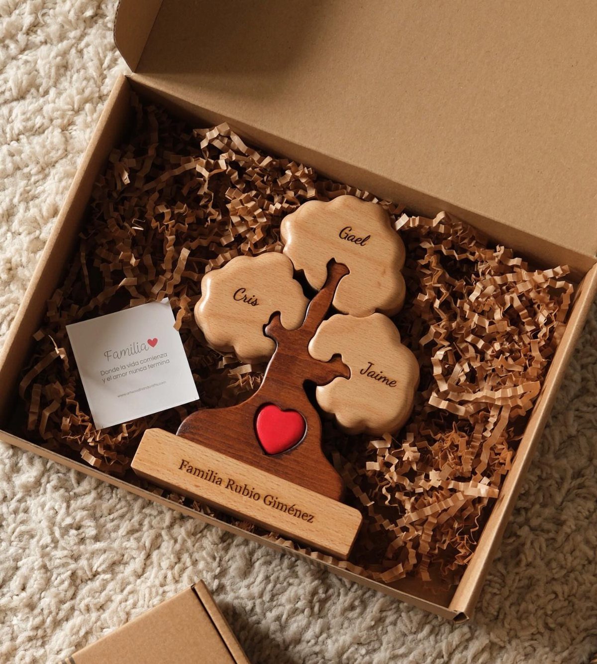 Wooden family tree sculpture with names and a red heart in a gift box