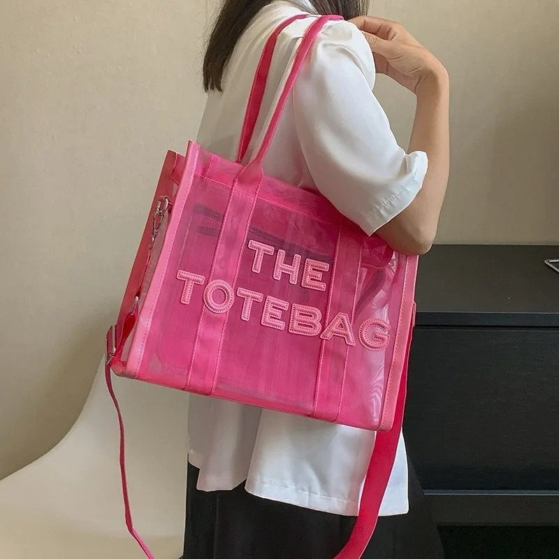 Bright pink translucent plastic tote bag with embossed text carried by a woman