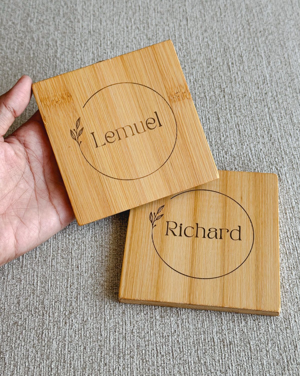 Two square wooden coasters engraved with the names Lemuel and Richard.