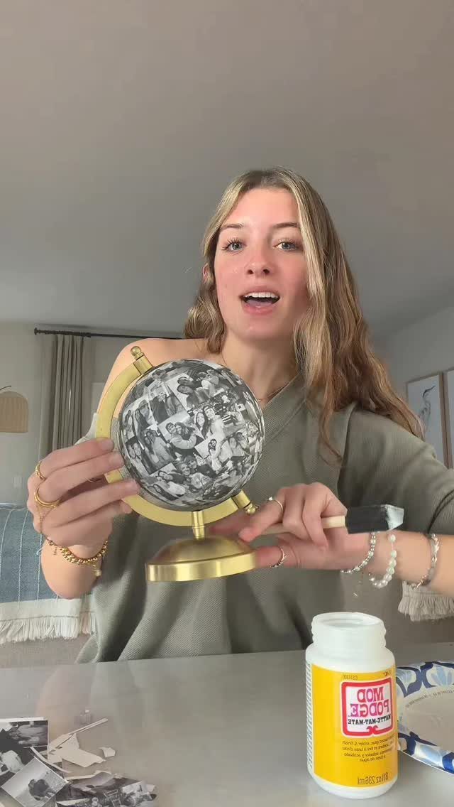 Woman holding a small globe decorated with black and white photo collages.