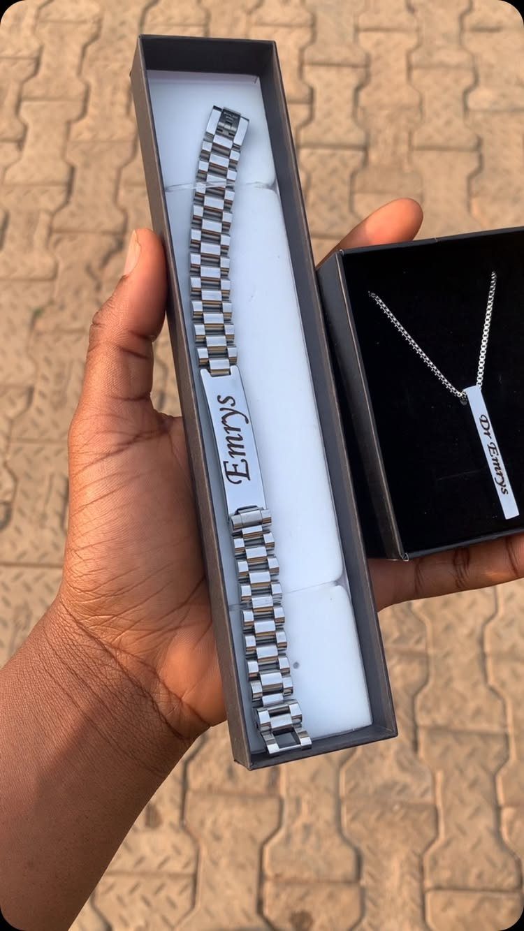 Silver engraved name bracelet and necklace in black boxes held by a hand.