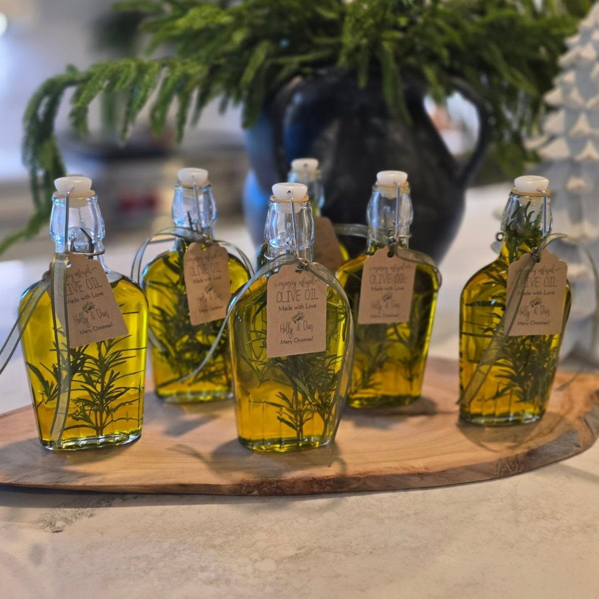 Small glass bottles of rosemary infused olive oil with gift tags on wood