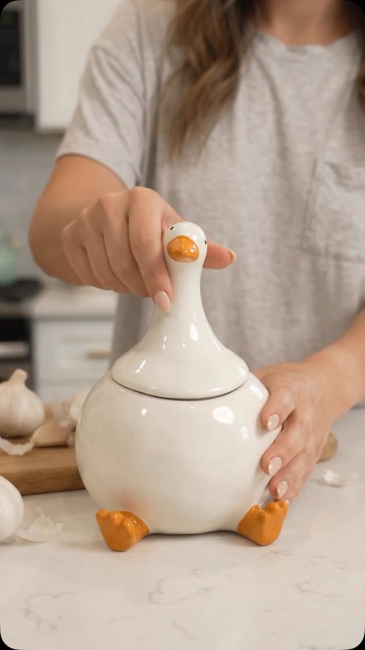 White ceramic goose jar held by hands on a marble kitchen counter