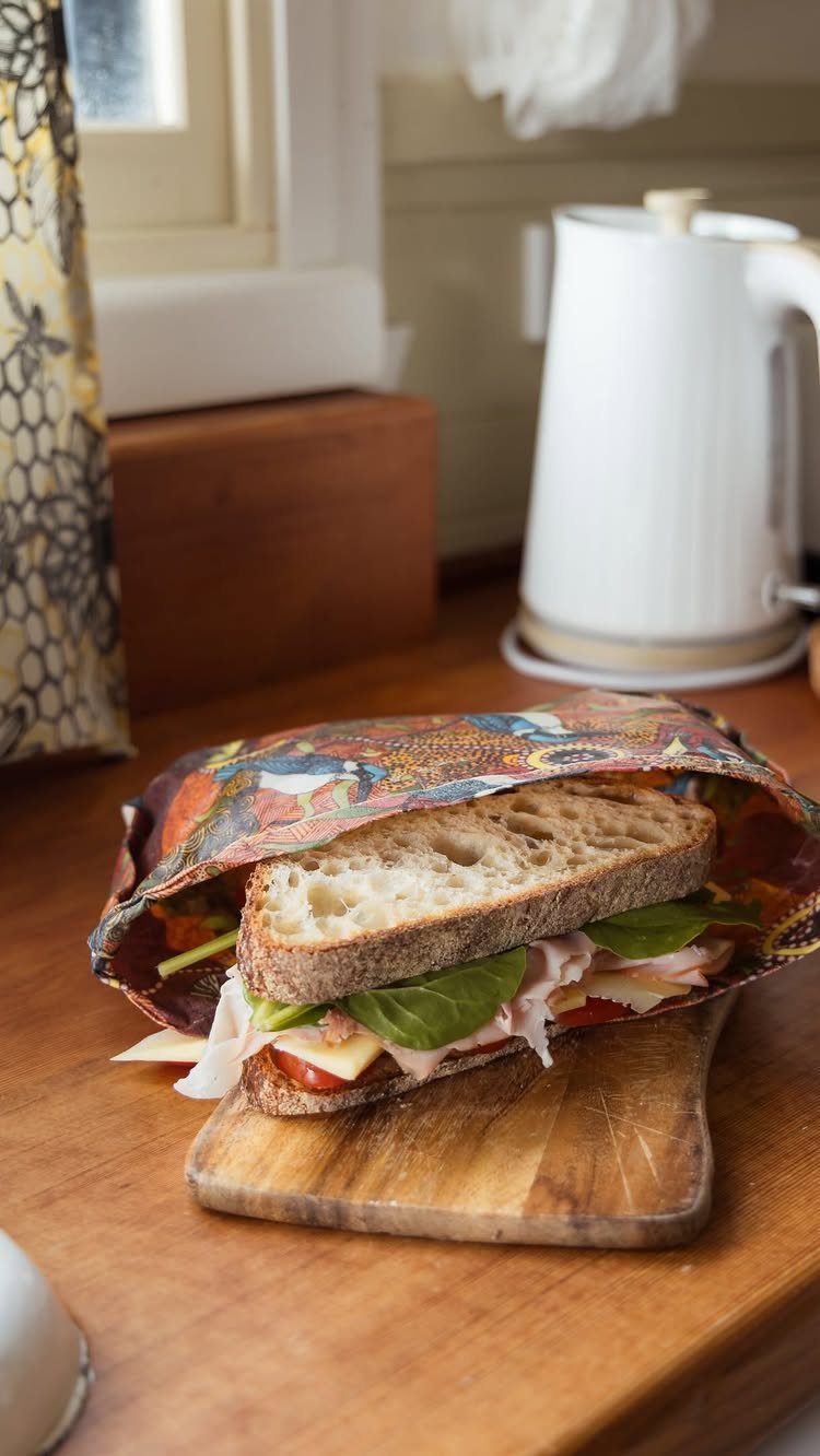 Sandwich on sourdough bread partially wrapped in a colorful patterned reusable food wrap.