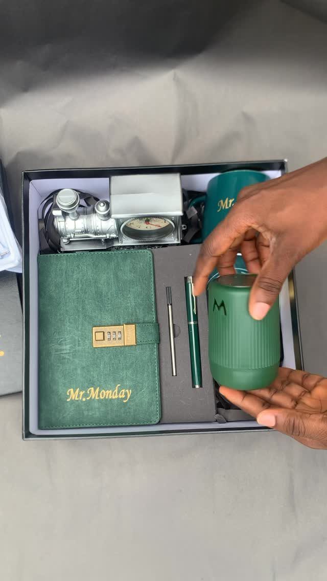 Green gift set with notebook, pen, and thermal cup held by hands