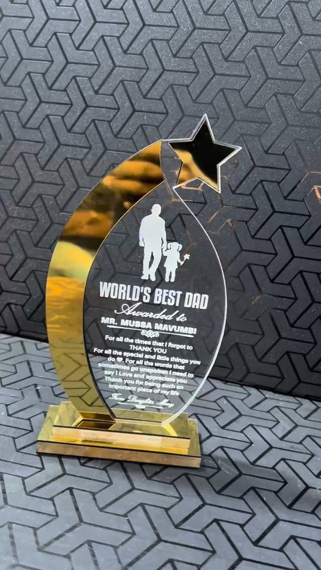 Gold and silver World's Best Dad trophy with father and child silhouette.