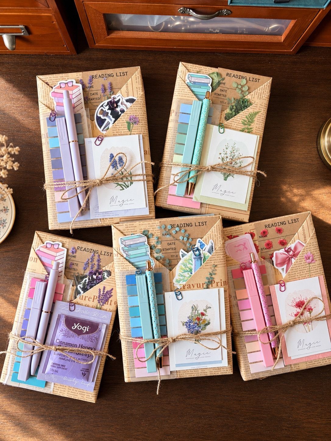 Stationery gift sets with notebooks, pens, and tea bags tied with twine.