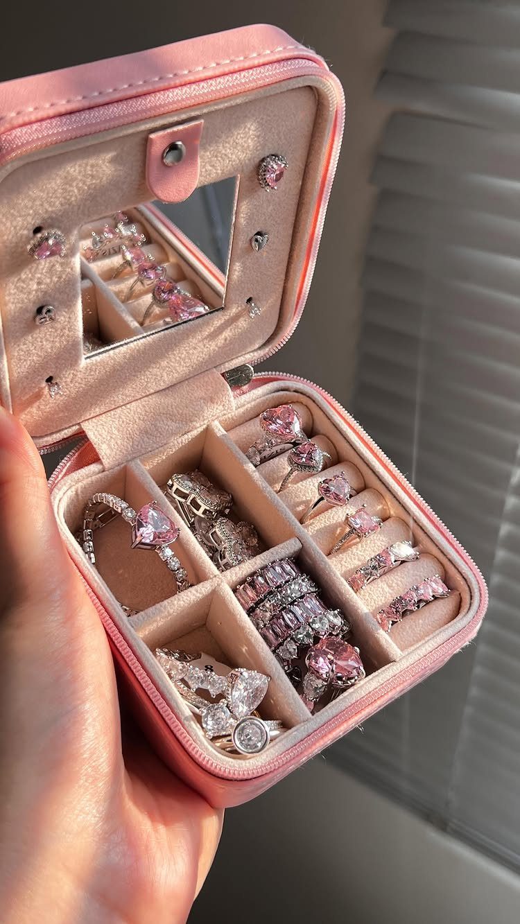 Pink velvet jewelry box filled with sparkling gemstone rings held in a hand