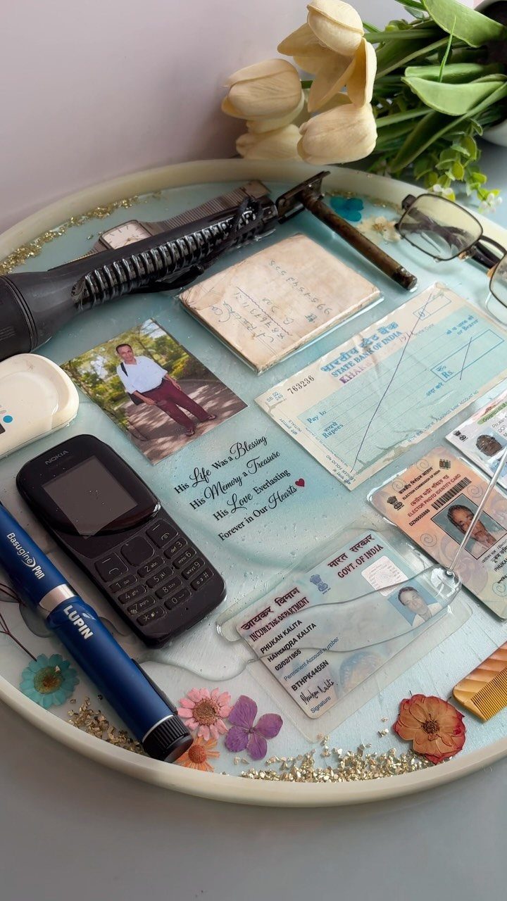 Resin preservation tray containing a vintage phone, photos, IDs, and dried flowers.