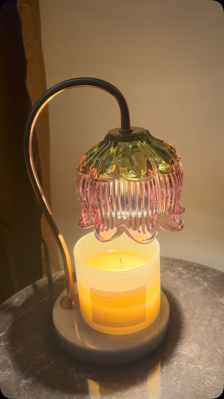 Candle warmer with a colorful flower-shaped glass shade and a glowing scented candle.