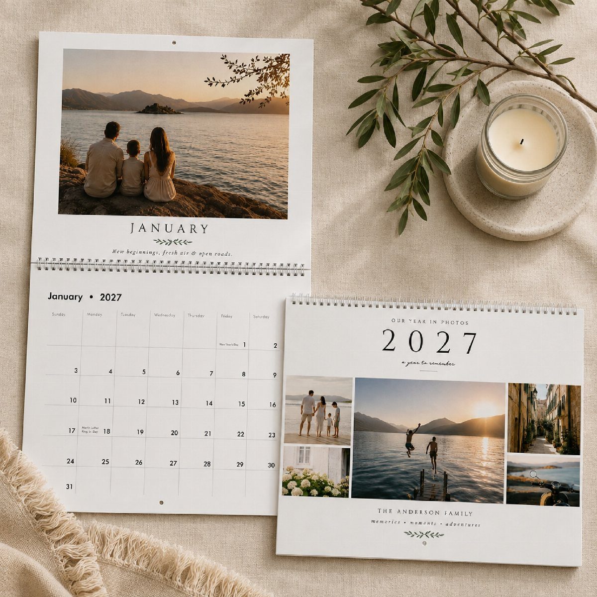 Personalized 2027 family photo calendars resting on a beige cloth with a candle.