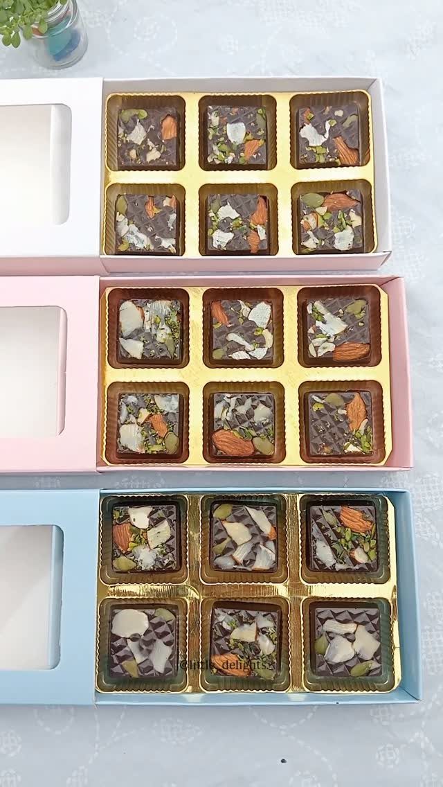 Three colorful gift boxes filled with assorted nut-topped chocolates in gold trays.