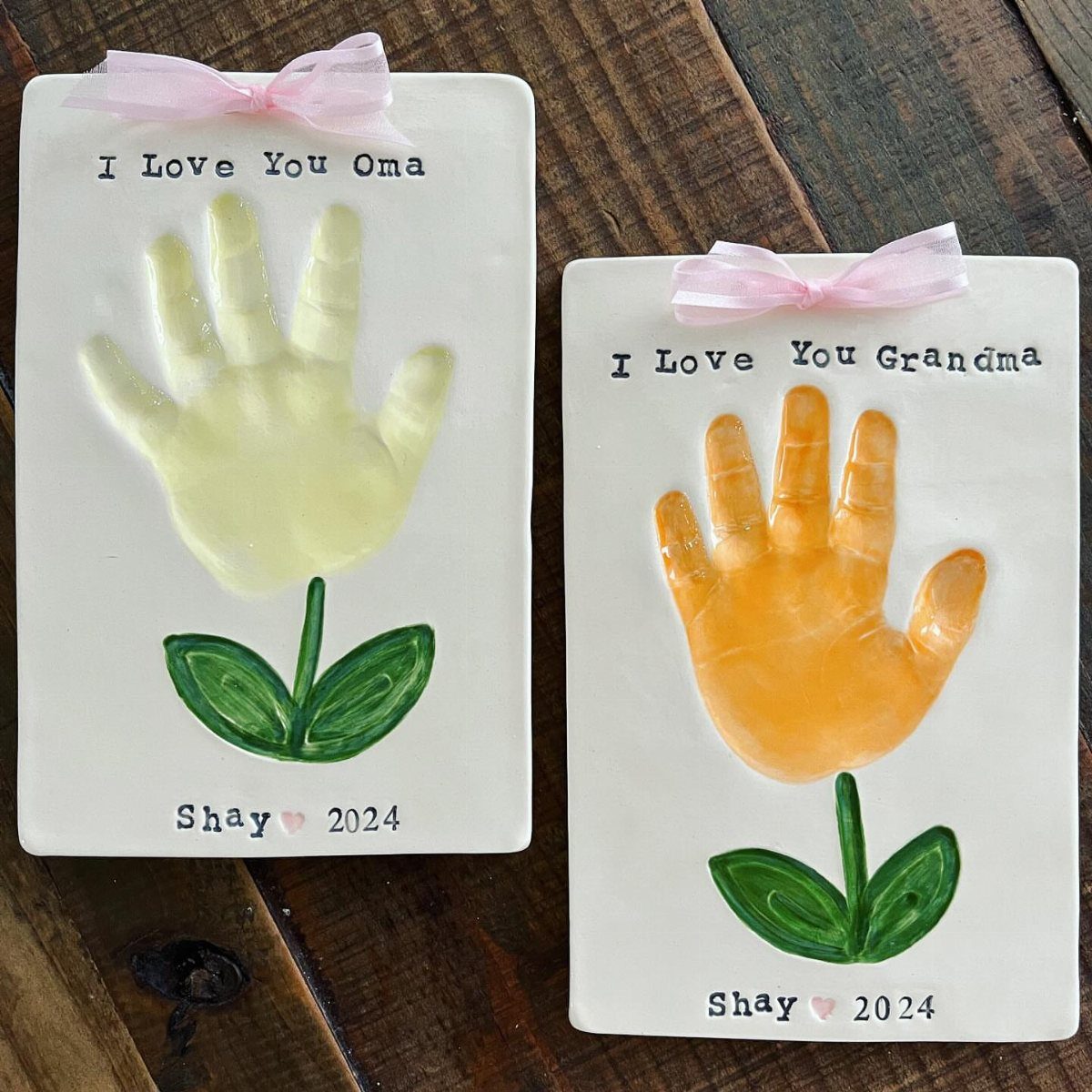 Two ceramic plaques with colorful child handprints shaped like flowers for grandparents.