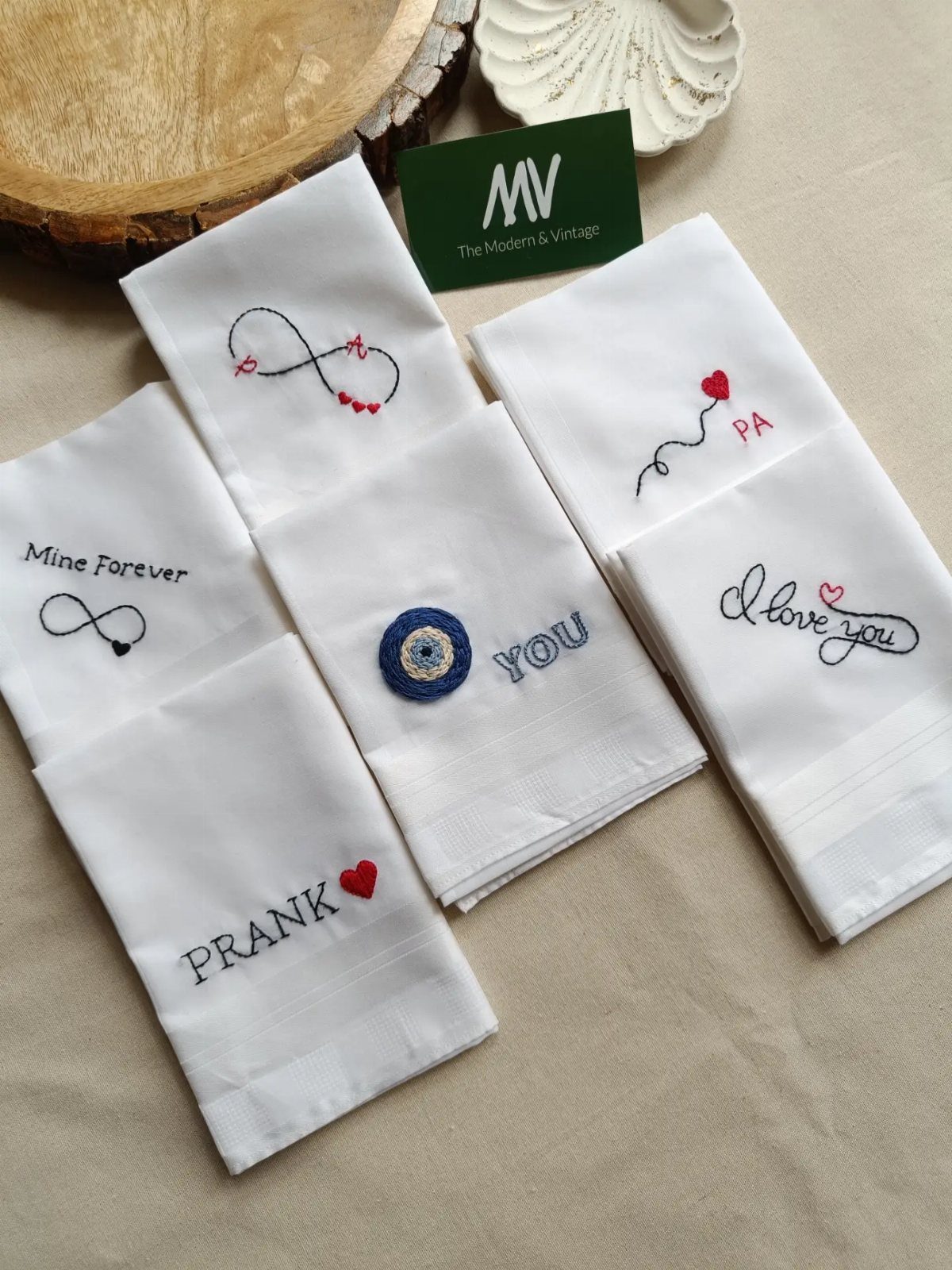 White embroidered handkerchiefs with sentimental messages and symbols on a beige background.