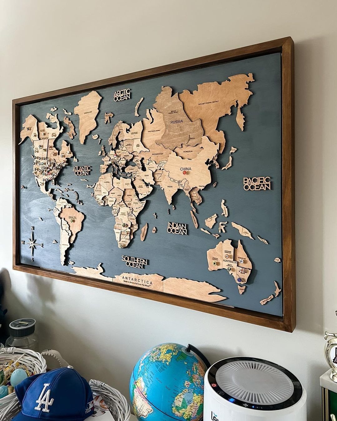 Wooden world map with light brown continents on a dark blue background in frame