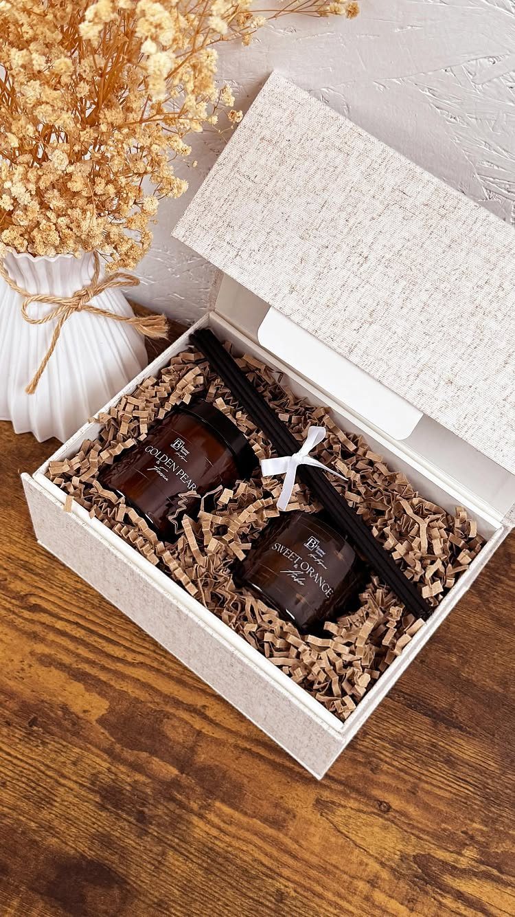 Gift box with two brown glass jars and dried flowers on wooden table