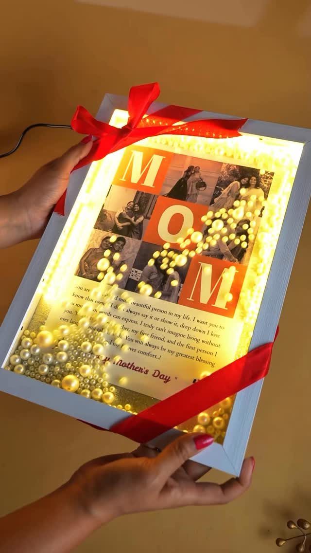 Illuminated white shadow box with photos, pearls, and red ribbon for Mother's Day.
