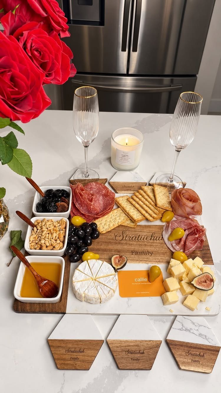 Engraved wooden and marble charcuterie board with meats, cheeses, and champagne glasses.