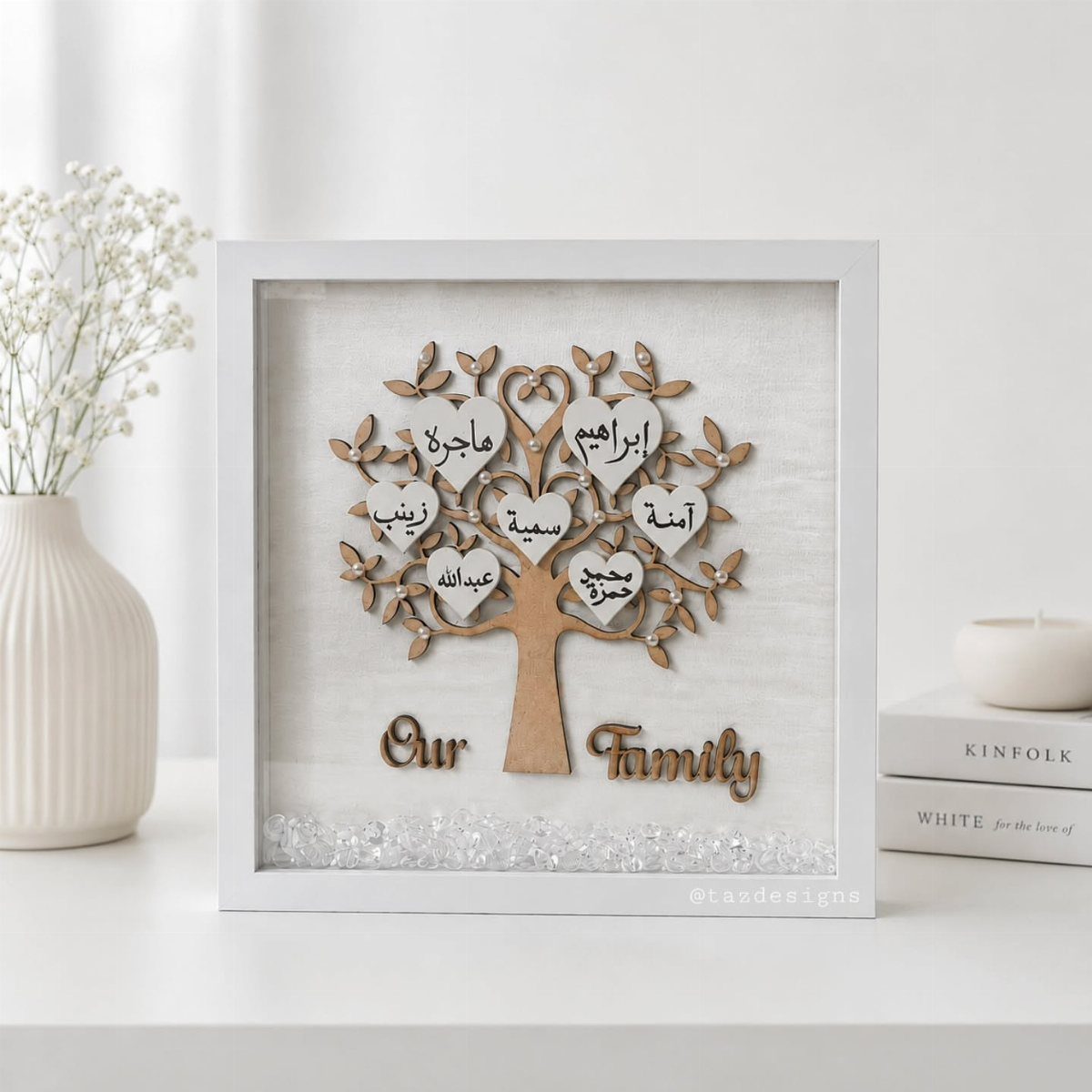 Wooden family tree sculpture with name hearts inside a white shadow box frame.